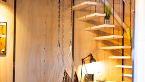 Een moderne woonkamer met een hangstoel, een bank en een trap met een plant.