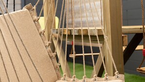 A wooden swing set with a beige hammock seat. - Bay Terminus - The Hanging Lodge (Saint-Blimont)