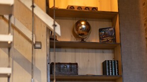 A wooden bookshelf with books and decorative items. - Bay Terminus - The Hanging Lodge (Saint-Blimont)