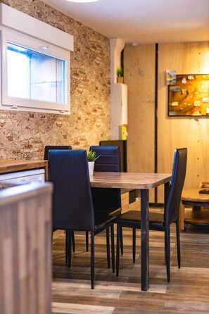 Een moderne eetruimte met een bakstenen muur, houten vloer en zwart beklede stoelen.
