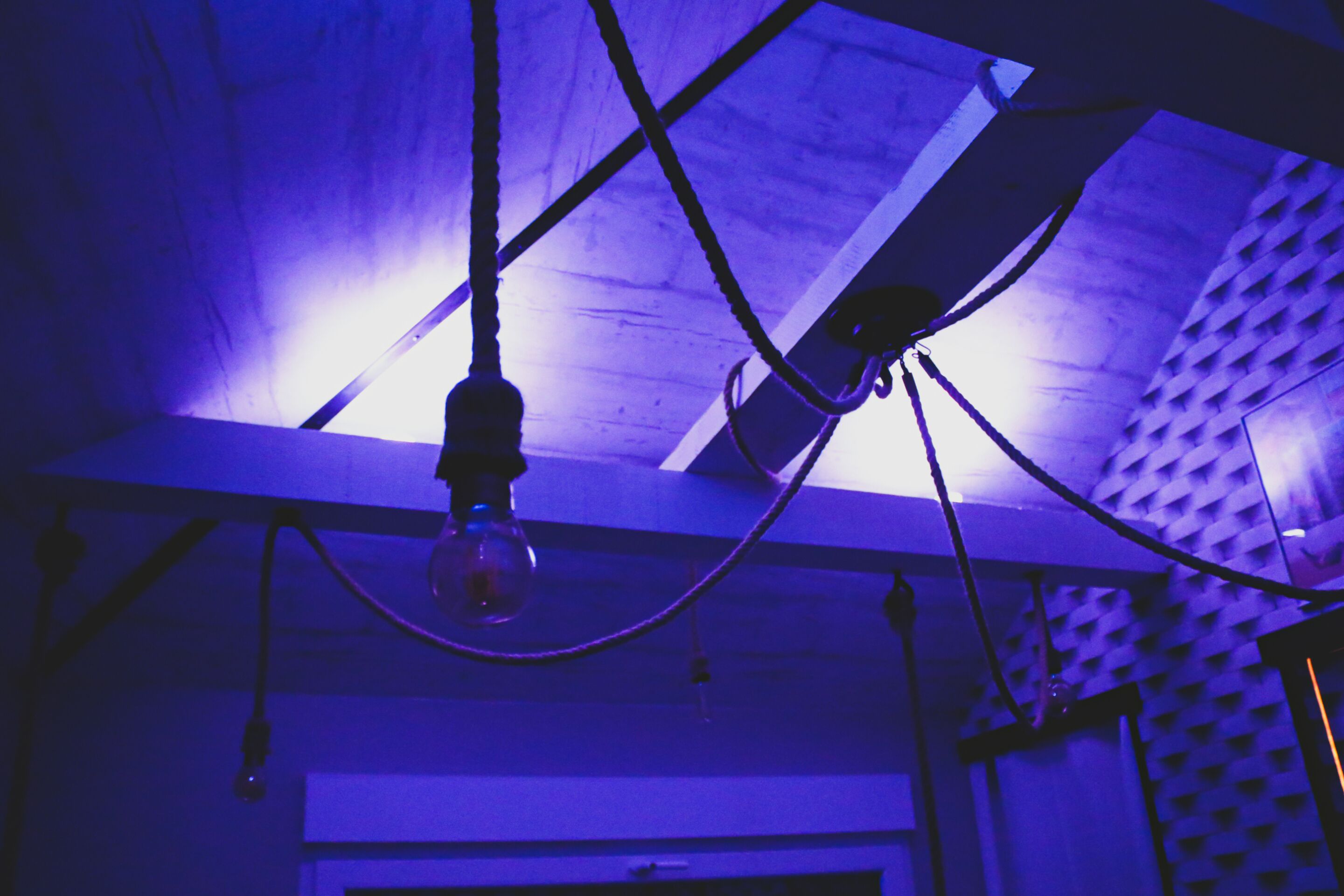 A room with a sloped ceiling, exposed beams, and a hanging light fixture.