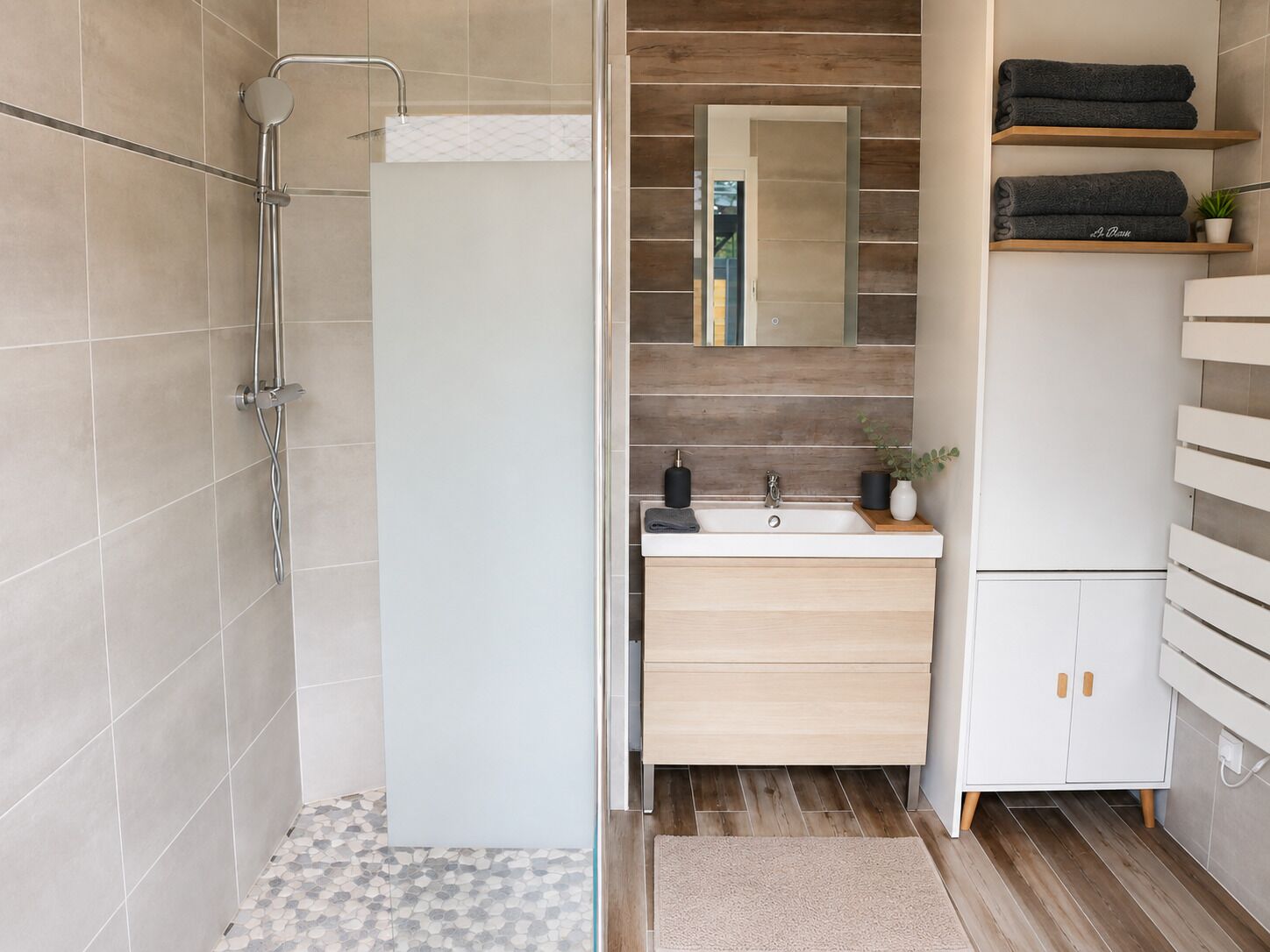A modern bathroom with a shower, a sink, and a cabinet.