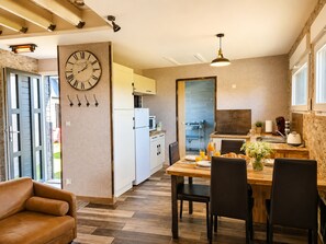 Une cuisine moderne avec un coin repas, comprenant une horloge, un plancher en bois et un canapé.