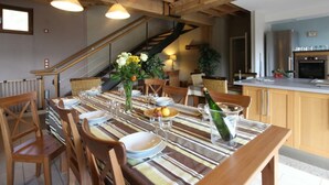 Un comedor con mantel a rayas, sillas de madera y una botella de champán.