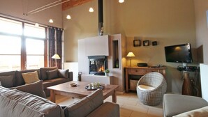 Una sala de estar acogedora con chimenea, sofás, una mesa de centro y una televisión.