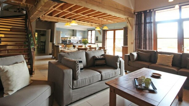 Amplia sala de estar con techo alto, vigas de madera y vista a la cocina.