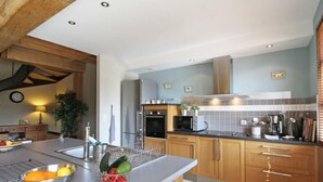Una cocina moderna con armarios de madera, un refrigerador de acero inoxidable y un horno empotrado.