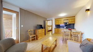 Een compact appartement met een kitchenette, een eethoek en een woonkamer met een bank en een televisie.