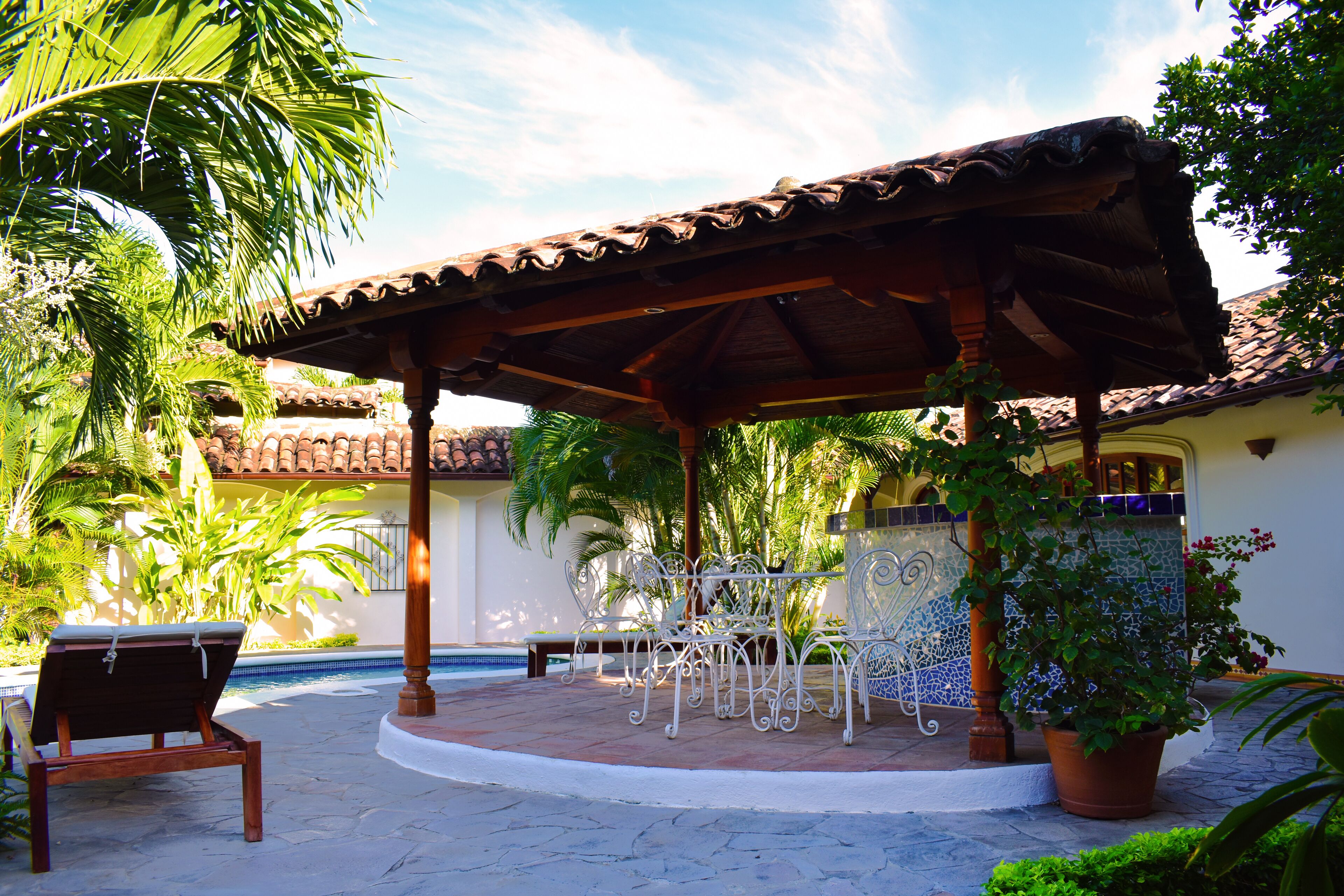 Un patio cubierto con piscina, mobiliario exterior y plantas en macetas.