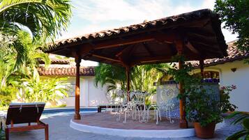 A covered patio with a pool, outdoor seating, and potted plants.