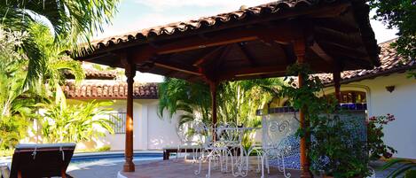 Un patio cubierto con piscina, mobiliario exterior y plantas en macetas.