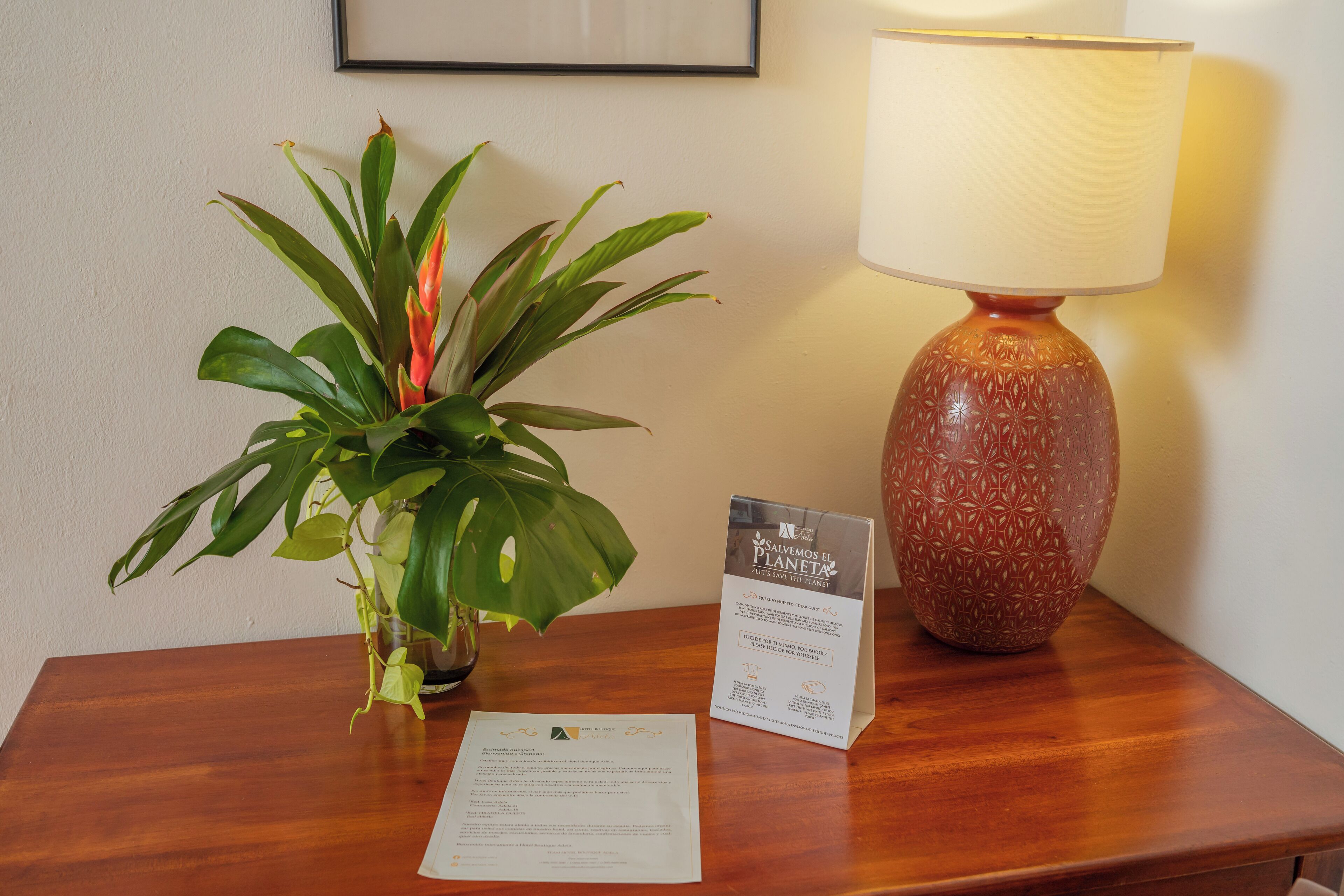 A wooden table with a potted plant, a lamp, and a sign.