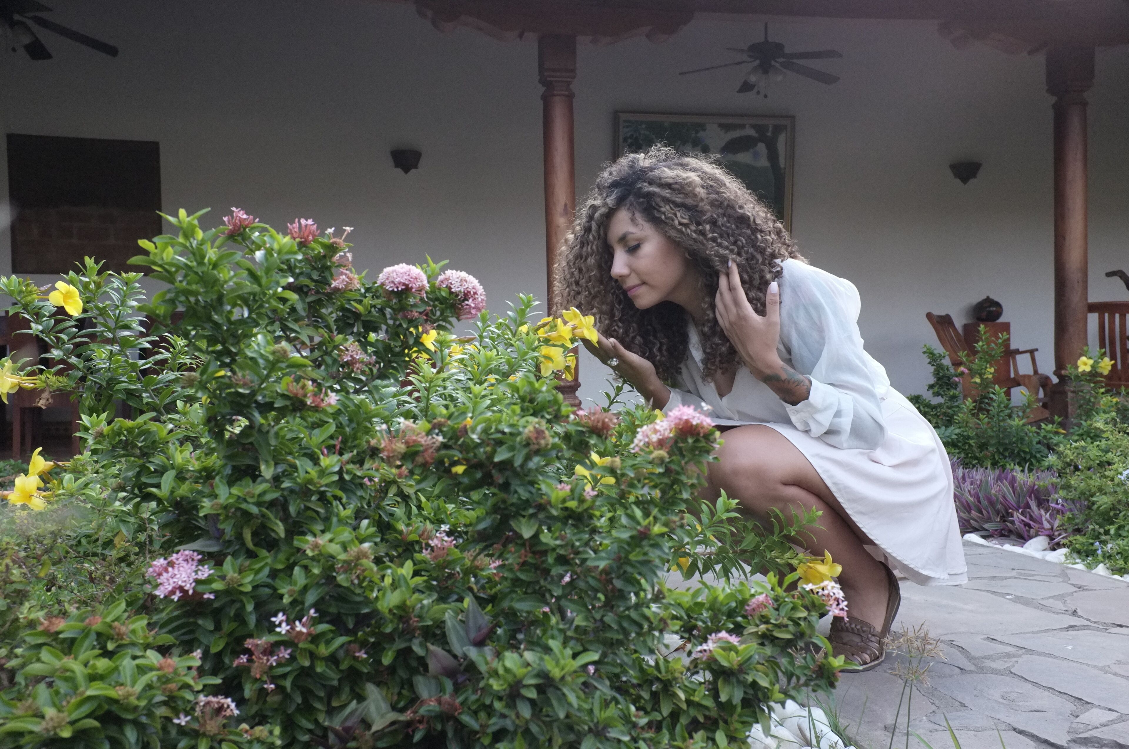 A person crouching near a garden with various plants and flowers.