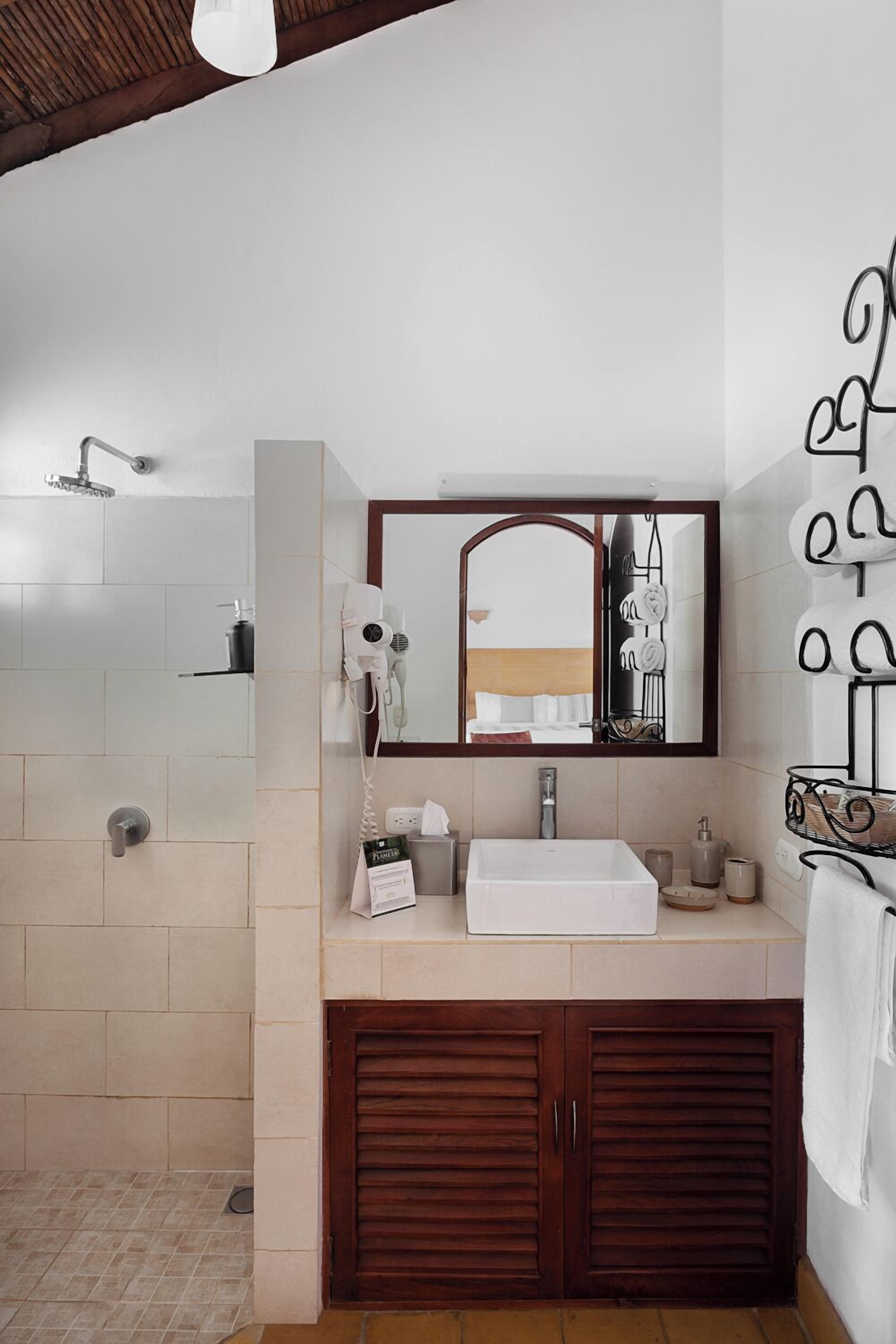 A bathroom with a white sink, a mirror, a hairdryer, and a shower.