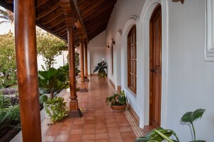 Un pasillo cubierto con suelo de baldosas, columnas de madera y plantas en macetas.