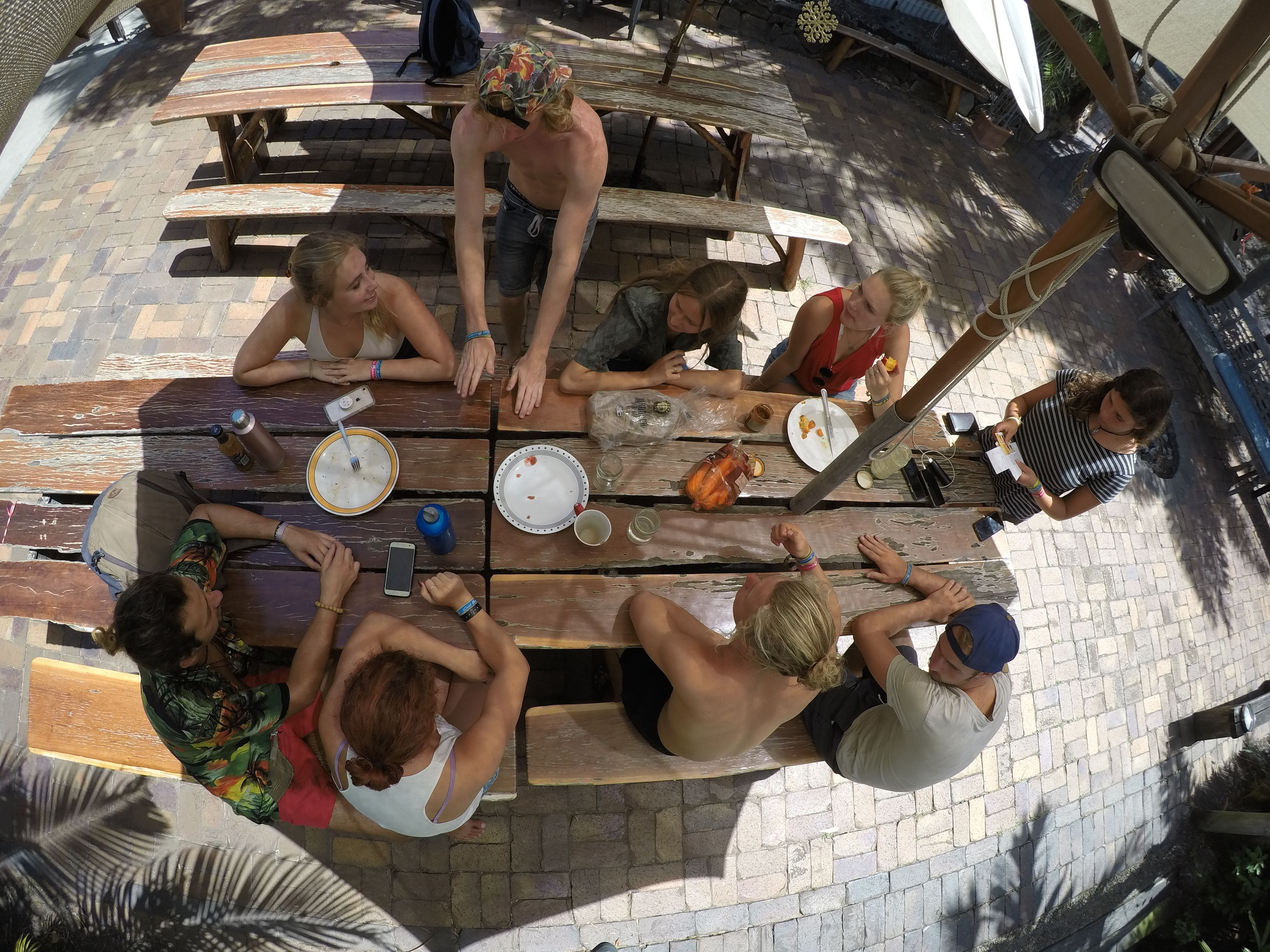A group of people seated around a wooden picnic table outdoors.