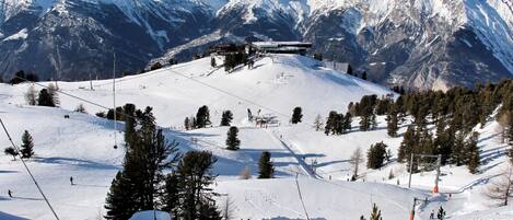 Une station de ski dotée d’un télésiège, de pistes enneigées et offrant une vue sur les montagnes.