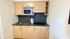 A compact kitchen with wooden cabinets, a stainless steel sink, a microwave, and a kettle. - Pracondu 1 103 - OUTDOOR & FUN  apartment 6 pers (Haute-Nendaz)
