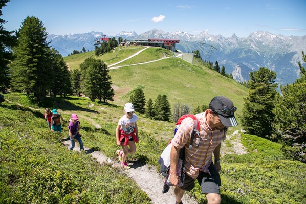 A mountainous hiking trail with a clear view of the surrounding landscape and distant mountains.