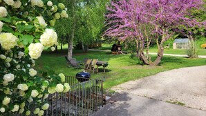Ein Garten mit Grill, Stühlen und einem Holztisch.
