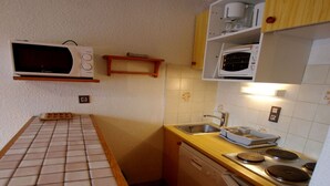Una cocina compacta con microondas, fregadero y estufa.