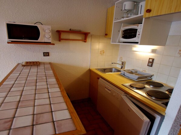Una cocina compacta con microondas, fregadero y estufa.