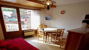 Una habitación acogedora con una cama, un escritorio y una silla. Se ve una ventana con vistas a edificios.