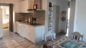 A compact kitchen with white cabinets, a built-in stove, and a dining area with a table set for two.
