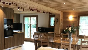 Ein modernes Wohnzimmer mit Sofa, Esstisch und Küchenbereich.