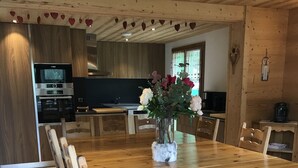 Ein Holzespeisesaal mit Stühlen, einer Vase mit Blumen und einer Küchenzeile mit Geräten.