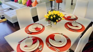 A dining area with a white table set for four, red placemats, and a vase of yellow flowers. - NEW Lakefront Disney Vacation Home (Kissimmee)