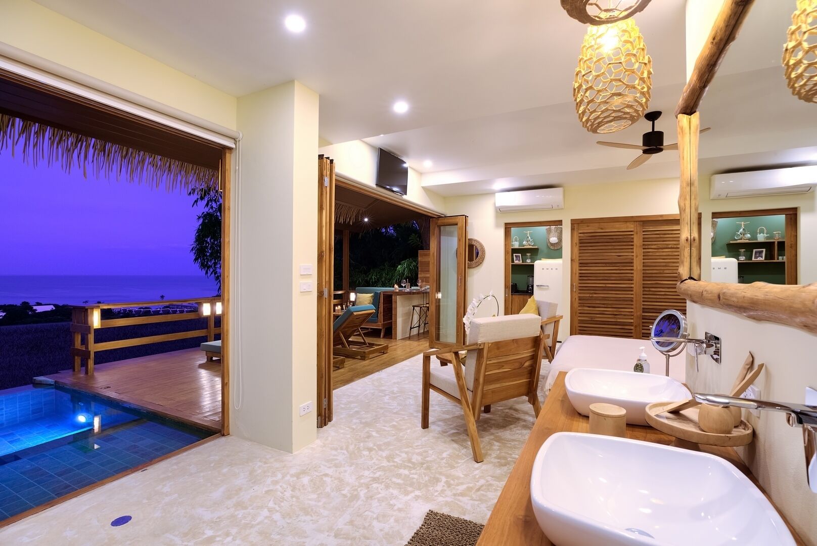 A modern bathroom with a large mirror, two sinks, and a view of the ocean.