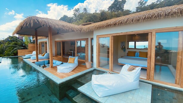 Un resort lujoso con piscina privada, zonas de descanso confortables y amplias puertas correderas de vidrio que dan a un dormitorio.