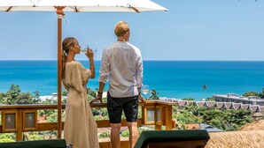 Una pareja bajo un paraguas contemplando una playa con vista despejada al océano.