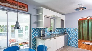 Eine moderne Küche mit weißen Schränken, einer blauen Fliesenrückwand und einem großen Fenster.