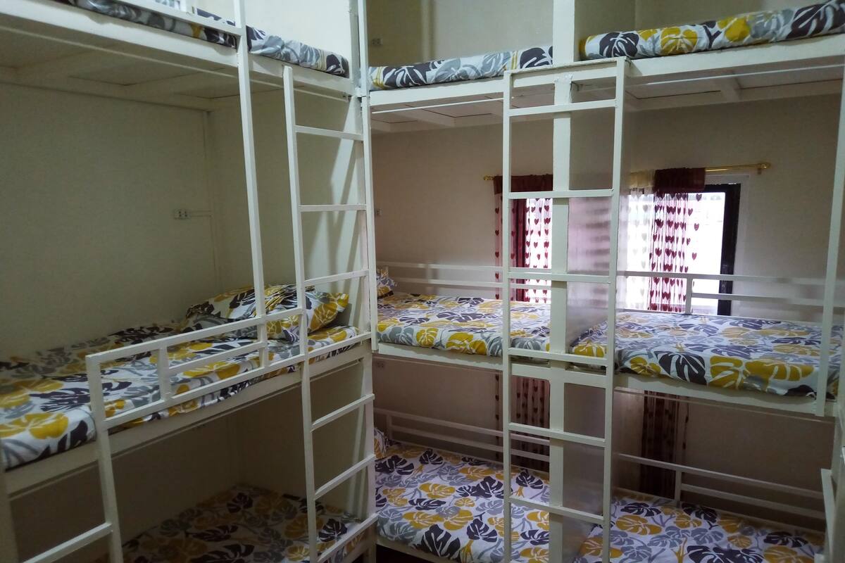 A bunk bed room with floral-patterned bedding and a window with heart-shaped curtains.