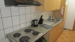 Una cucina con piano cottura, lavello e pensili in legno.
