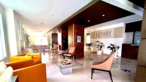 A modern lobby with orange sofas, a glass coffee table, and a reception desk labeled "LEVENT". - Aruba Eagle Beach One Happy Island Vacation Waiting For You!! (Oranjestad-West)