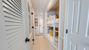 A hallway with white doors, a tiled floor, and a bed with yellow bedding in a room at the end. - Welcome to beautiful Gulf Shores! *Location!! Location!! Location!!* #TheHangout (Gulf Shores)