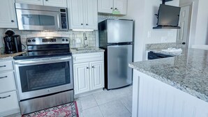 A modern kitchen with white cabinetry, stainless steel appliances, a granite countertop, and a built-in oven. - Welcome to beautiful Gulf Shores! *Location!! Location!! Location!!* #TheHangout (Gulf Shores)