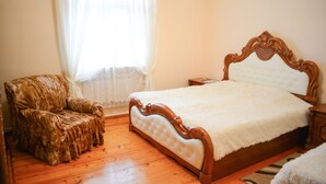 Un dormitorio con una cama de madera, una silla y un ventanal con cortinas.