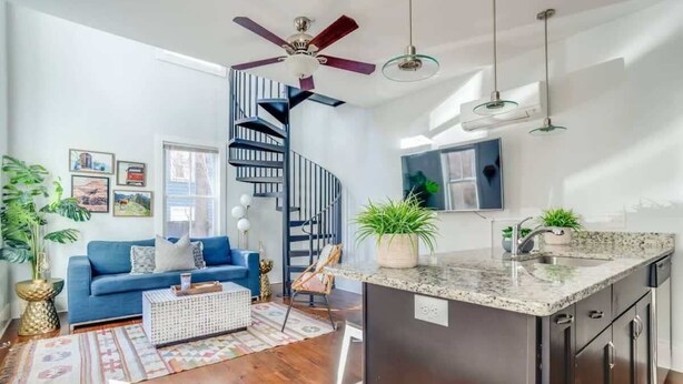 A modern living room with a blue sofa, a coffee table, and a spiral staircase.