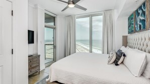 A bedroom with a large bed, a ceiling fan, a view of the beach, and a sliding glass door to the outside. - Tower 3- Amazing Gulf Views at Portofino 3-1909 (Pensacola Beach)