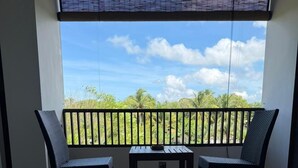 Ein Balkon mit zwei Stühlen und einem Tisch, Blick auf Palmen und ein gefliester Boden.