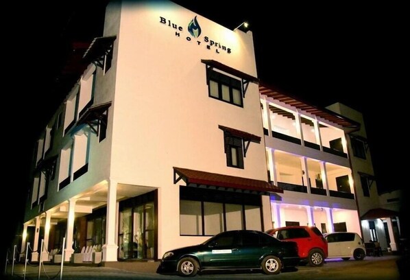 Un hotel de dos pisos con techo plano y un letrero que dice 'Blue Spring Hotels'.