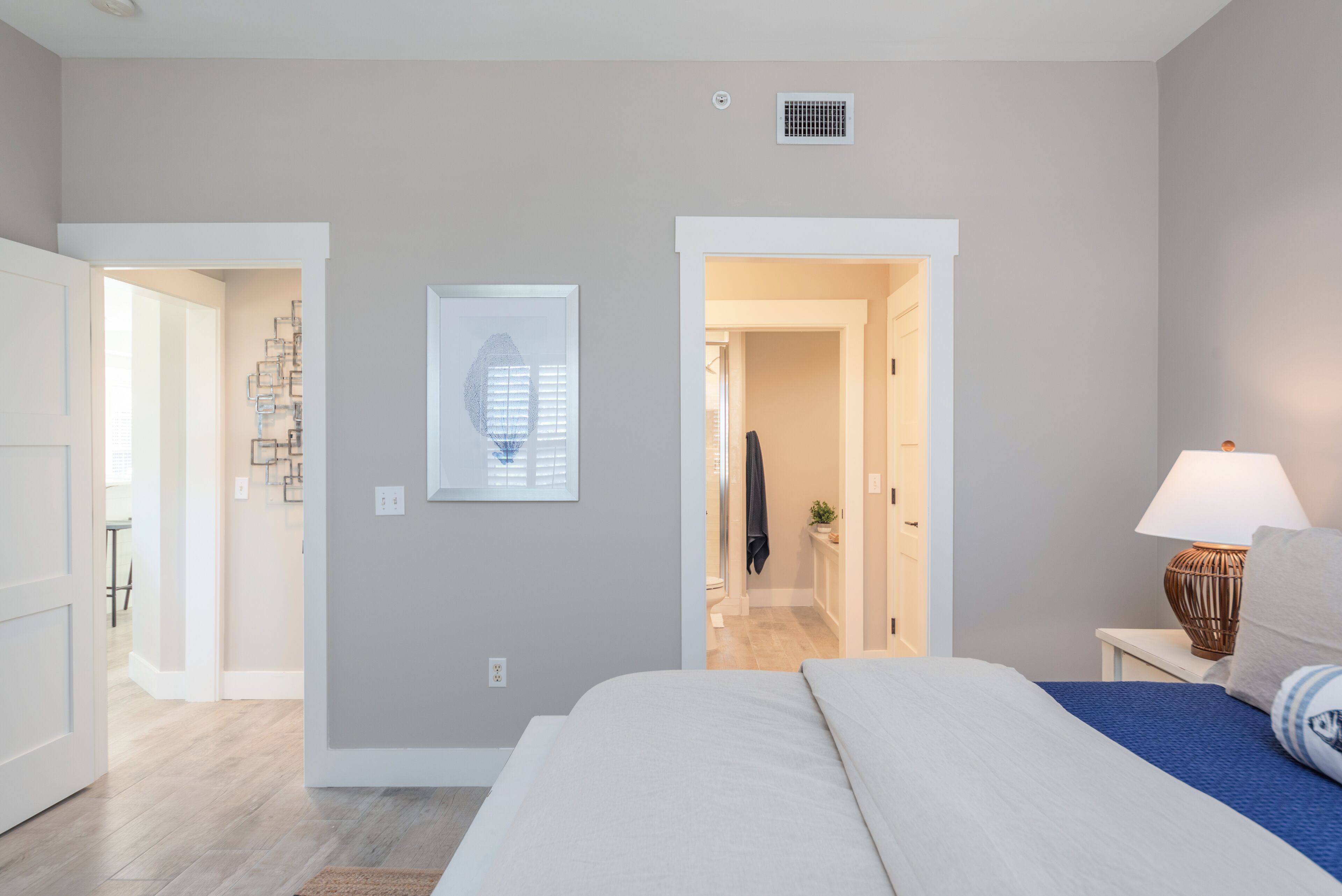 A bedroom with a bed, a nightstand, a lamp, and a wall-mounted picture.