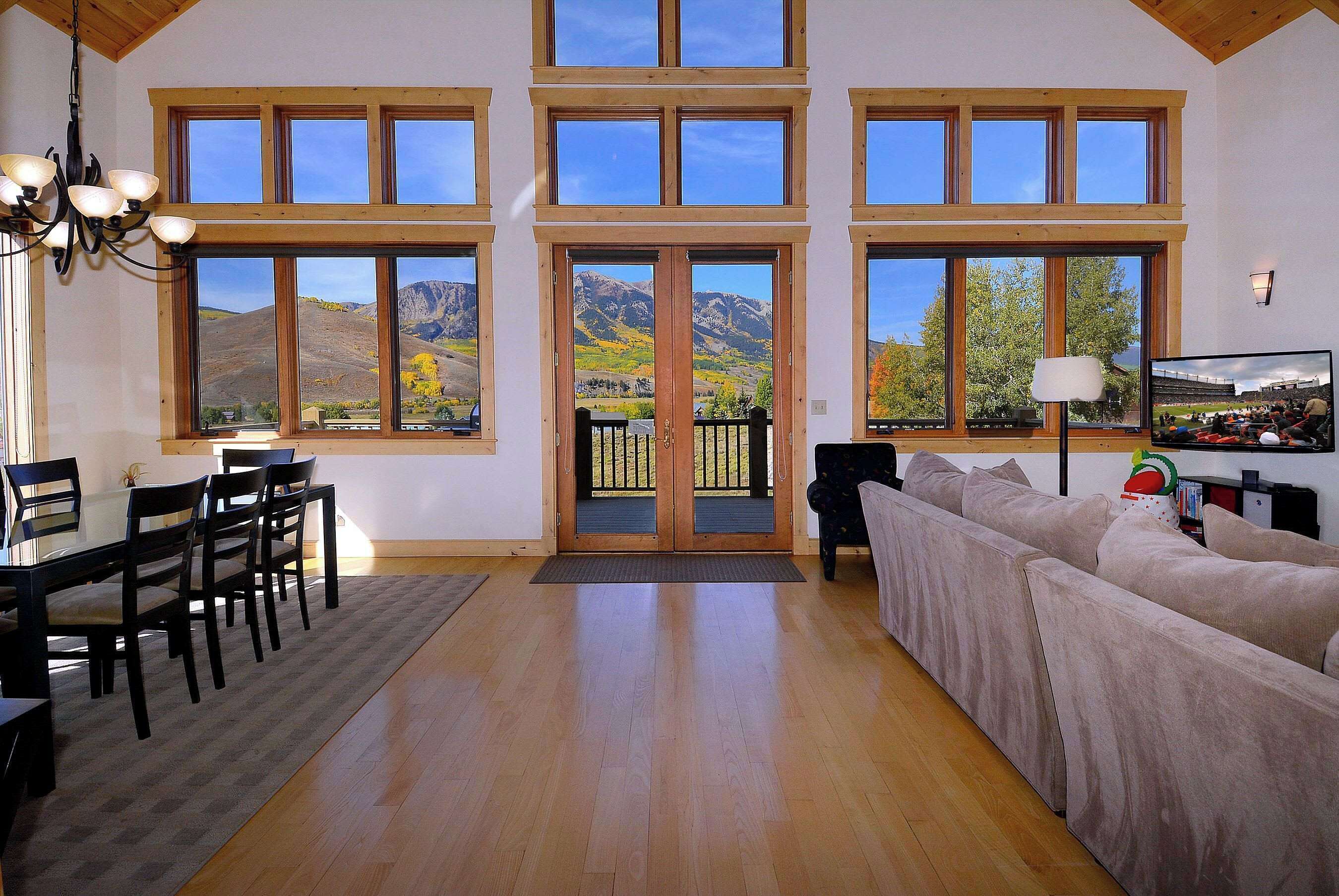 A spacious living room with a large window, a dining area, and a sofa.