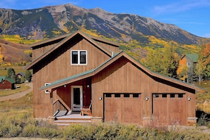 Eine Holz-Blockhütte mit Veranda, Garage und Bergblick.