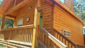 A wooden cabin with a balcony, a chimney, and a door with a number plate.