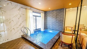 A spa area with a hot tub, wooden flooring, and a brick wall. - Kavish Holiday Hill Resort (Udaipur)